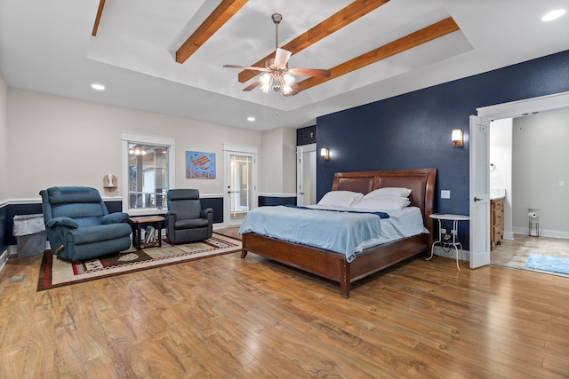 bedroom with ceiling fan, beamed ceiling, hardwood / wood-style flooring, and a raised ceiling