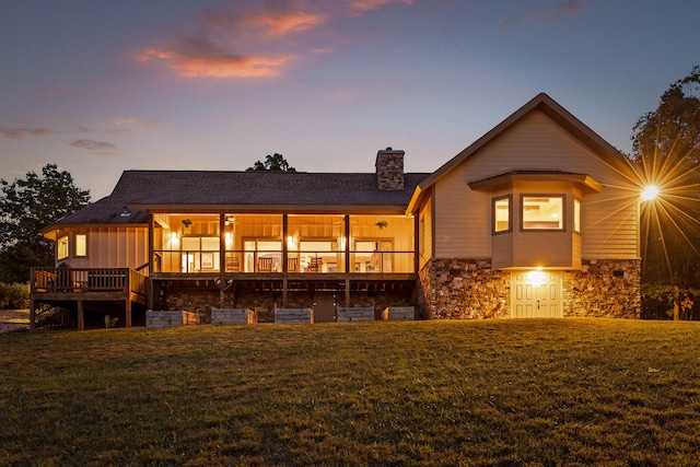 back house at dusk with a yard and a wooden deck