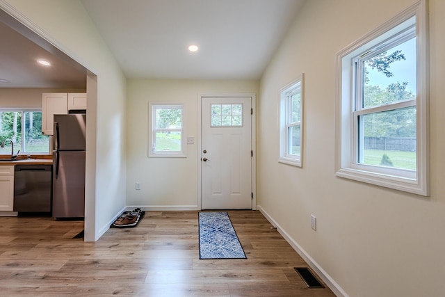 doorway with baseboards, visible vents, light wood-type flooring, and a sink