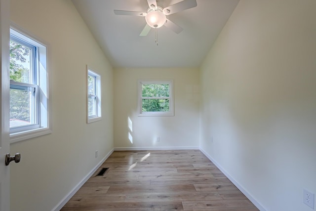 spare room with baseboards, visible vents, light wood-style flooring, and vaulted ceiling