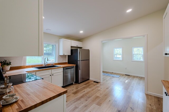 kitchen featuring wood counters, stainless steel appliances, lofted ceiling, white cabinetry, and a sink