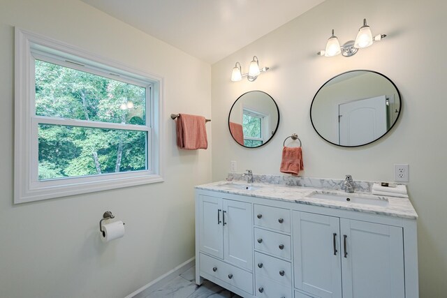 full bath with marble finish floor, a sink, double vanity, and baseboards