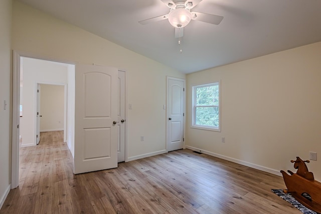 unfurnished bedroom featuring a ceiling fan, baseboards, vaulted ceiling, and wood finished floors