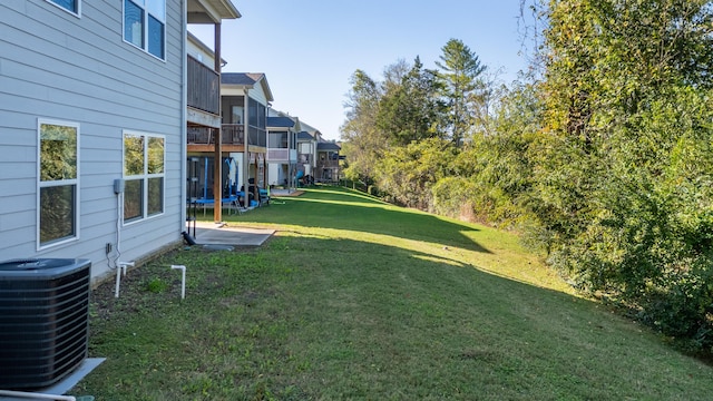 view of yard with a patio, central AC, and a balcony