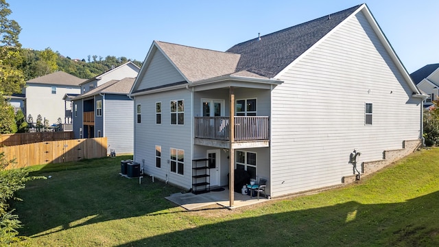 rear view of house with central air condition unit, a lawn, and a balcony