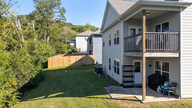 view of property exterior featuring a patio, cooling unit, a yard, and a balcony