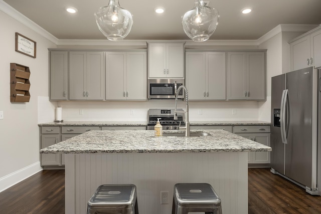 kitchen with an island with sink, dark hardwood / wood-style floors, stainless steel appliances, and pendant lighting