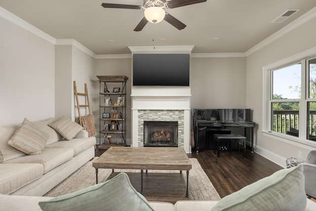 living room featuring ceiling fan, crown molding, a fireplace, and dark hardwood / wood-style floors