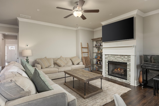 living room featuring dark wood-type flooring, a fireplace, crown molding, and ceiling fan