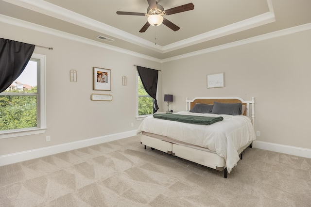 bedroom with crown molding, light colored carpet, a raised ceiling, and ceiling fan