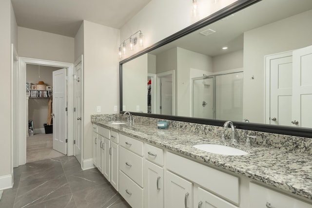 bathroom featuring a shower with door and vanity