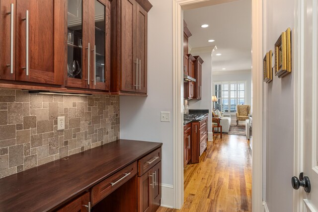 interior space featuring light hardwood / wood-style flooring, crown molding, and tasteful backsplash