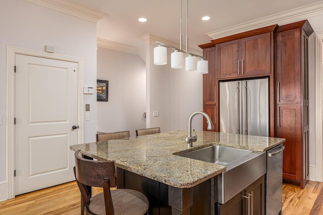 kitchen with stainless steel appliances, sink, a center island with sink, pendant lighting, and crown molding