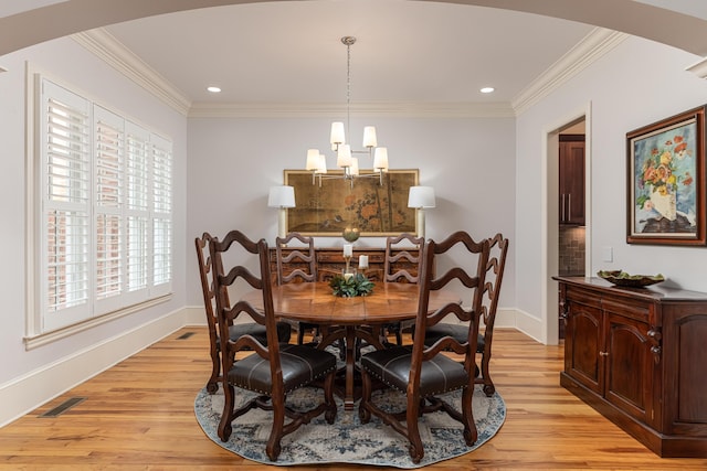 dining area with a healthy amount of sunlight, light hardwood / wood-style flooring, ornamental molding, and a chandelier