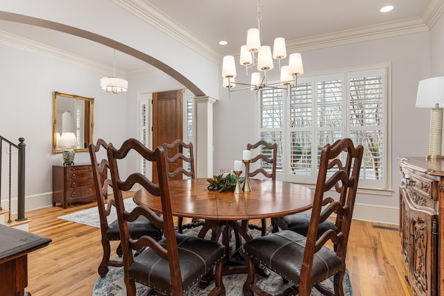 dining space with a notable chandelier, light hardwood / wood-style flooring, crown molding, and decorative columns