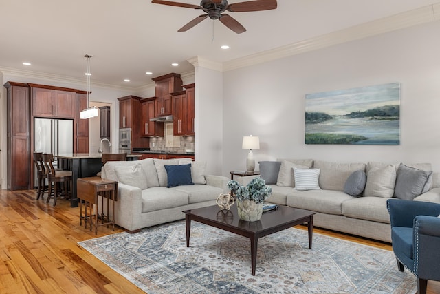 living room with light hardwood / wood-style floors, ceiling fan, and crown molding