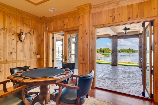 playroom with a water view, wooden walls, hardwood / wood-style floors, and ceiling fan