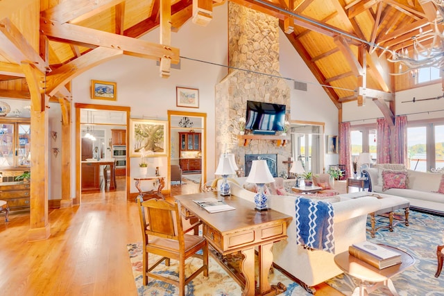 living room featuring light hardwood / wood-style flooring, a fireplace, high vaulted ceiling, and beamed ceiling