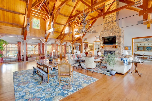 living room with beamed ceiling, wooden ceiling, a fireplace, and high vaulted ceiling