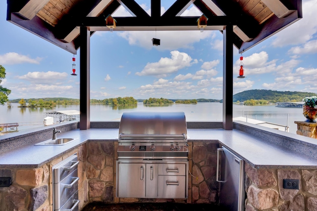 view of patio with sink, grilling area, a water view, and an outdoor kitchen