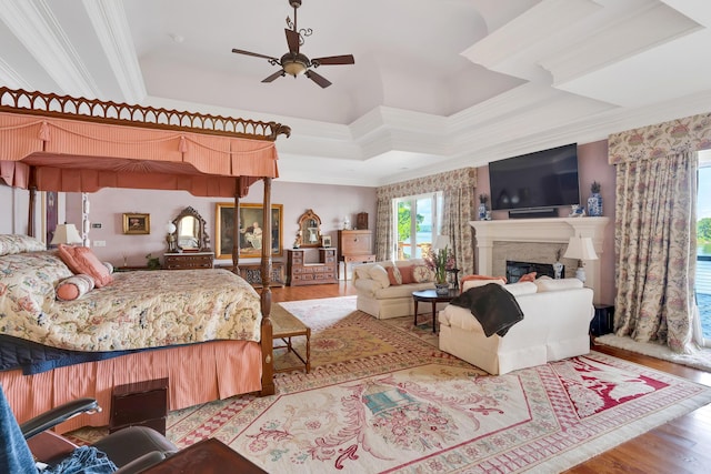 bedroom with a raised ceiling, crown molding, ceiling fan, and light wood-type flooring