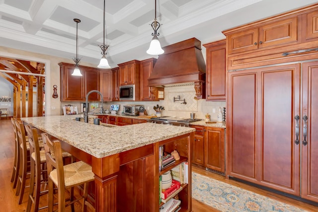 kitchen with decorative light fixtures, sink, custom exhaust hood, coffered ceiling, and stainless steel appliances