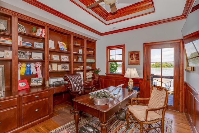 home office with built in desk, ornamental molding, a raised ceiling, ceiling fan, and hardwood / wood-style floors