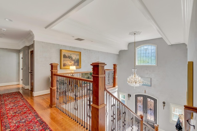 hall with french doors, crown molding, a chandelier, and light hardwood / wood-style floors