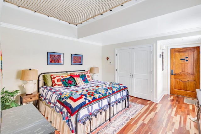 bedroom featuring crown molding, light hardwood / wood-style floors, and a closet