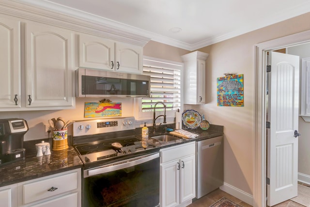 kitchen with sink, crown molding, appliances with stainless steel finishes, white cabinetry, and dark stone countertops