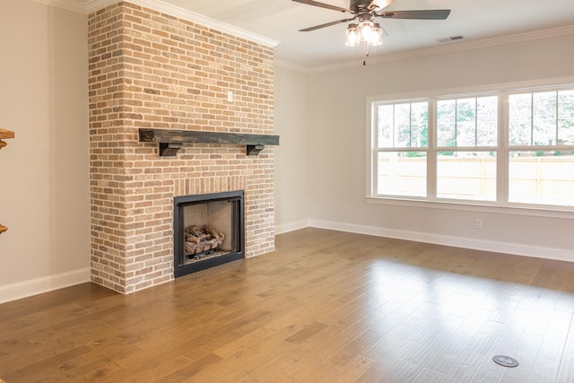 unfurnished living room featuring crown molding, a brick fireplace, wood-type flooring, and a healthy amount of sunlight