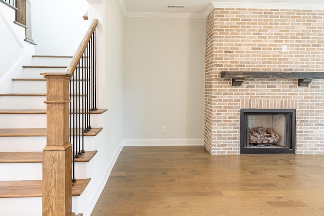 unfurnished living room featuring crown molding, a brick fireplace, and hardwood / wood-style floors