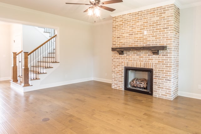 unfurnished living room with ornamental molding, hardwood / wood-style floors, and a brick fireplace