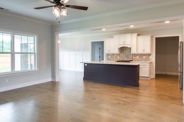 kitchen with a kitchen island with sink, light hardwood / wood-style flooring, and white cabinets