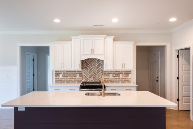 kitchen featuring a center island with sink, ornamental molding, and white cabinets