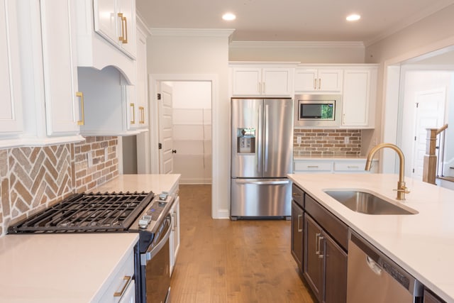 kitchen featuring stainless steel appliances, backsplash, sink, white cabinetry, and light hardwood / wood-style floors