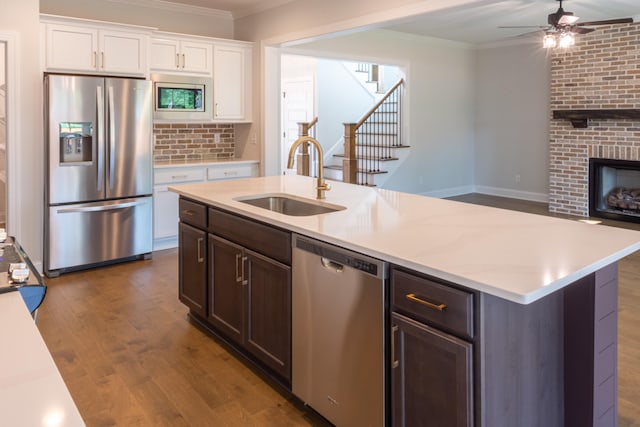 kitchen with appliances with stainless steel finishes, white cabinetry, dark wood-type flooring, crown molding, and sink