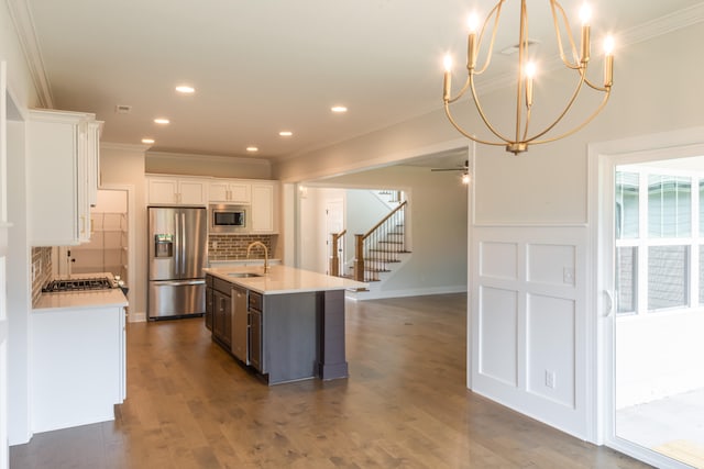 kitchen with a center island with sink, dark hardwood / wood-style flooring, appliances with stainless steel finishes, backsplash, and white cabinetry