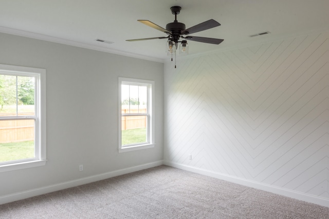 carpeted spare room with ornamental molding, plenty of natural light, and ceiling fan