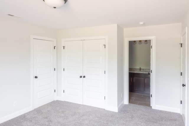 unfurnished bedroom featuring ensuite bath and light colored carpet