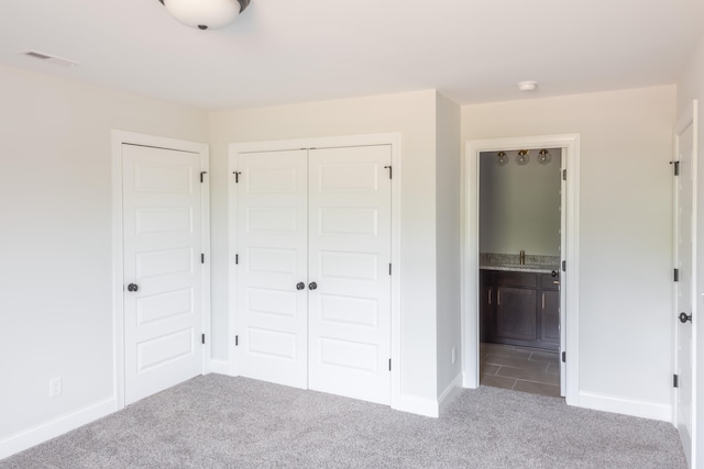 unfurnished bedroom featuring ensuite bath and carpet