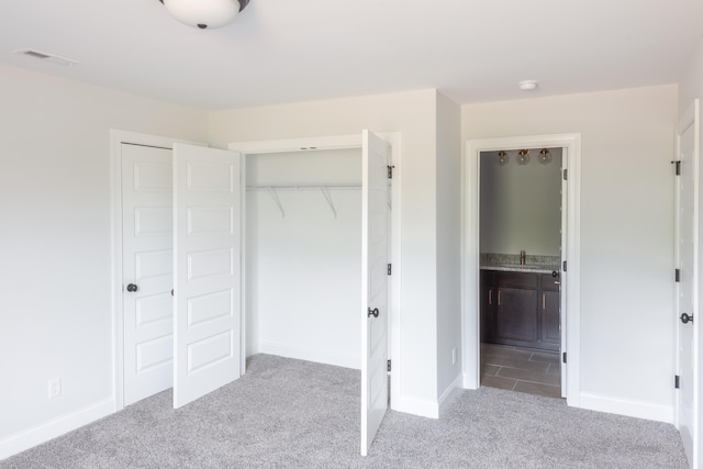 unfurnished bedroom featuring ensuite bathroom and light colored carpet