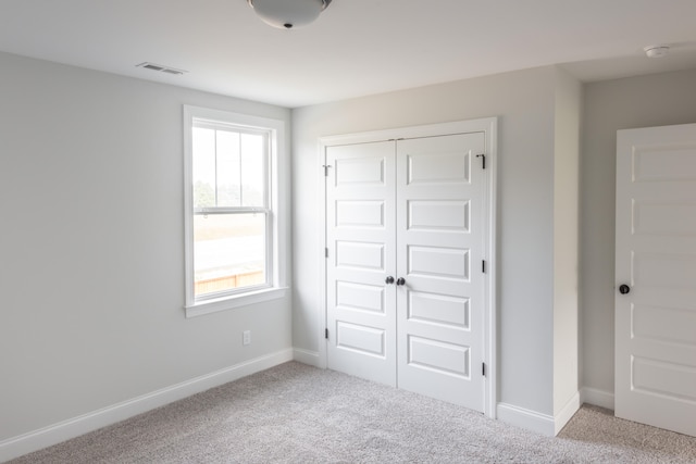 unfurnished bedroom with a closet and light carpet