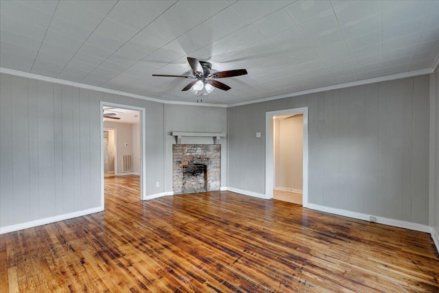 unfurnished living room featuring ornamental molding, a fireplace, wood-type flooring, and wood walls