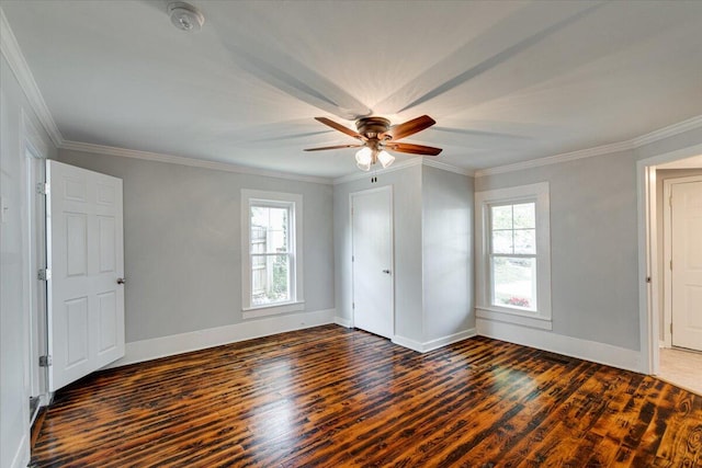 unfurnished bedroom featuring dark wood-type flooring, ceiling fan, multiple windows, and ornamental molding