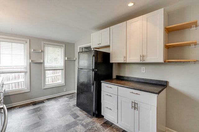 kitchen featuring black refrigerator, lofted ceiling, and white cabinets