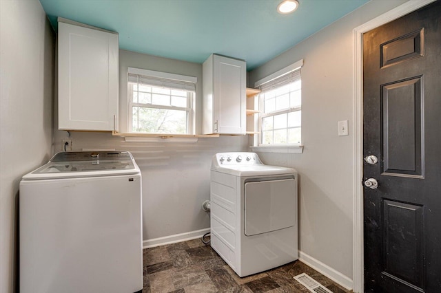 washroom with washing machine and dryer, cabinets, and plenty of natural light