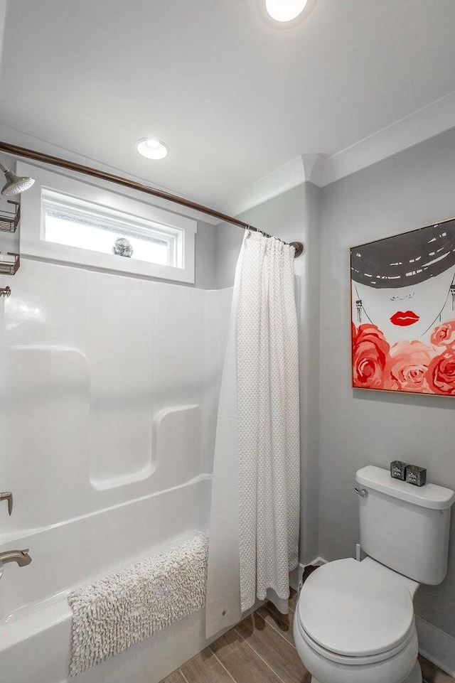 bathroom featuring shower / bathtub combination with curtain, hardwood / wood-style flooring, and toilet