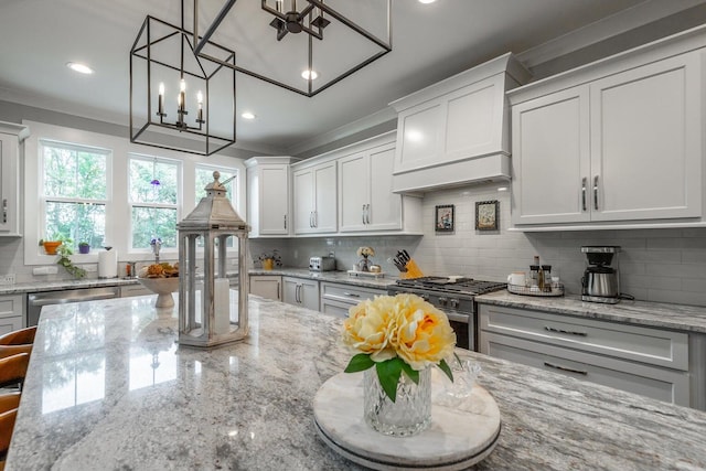 kitchen featuring light stone counters, appliances with stainless steel finishes, decorative light fixtures, and white cabinetry