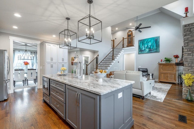 kitchen featuring gray cabinetry, ceiling fan with notable chandelier, pendant lighting, a center island, and dark hardwood / wood-style floors